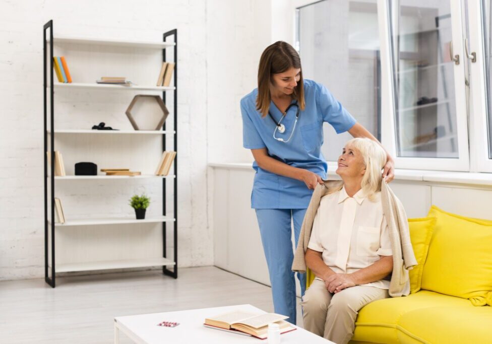 Caregiver assisting elderly woman with cardigan